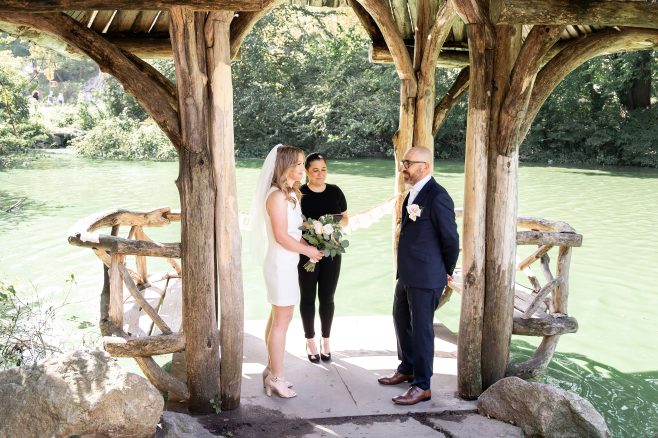 Wedding officiant Stephanie Mercurio is officiating a ceremony at Wagner Cove. The bride is wearing a short dress and the groom is dress in a blue suit.