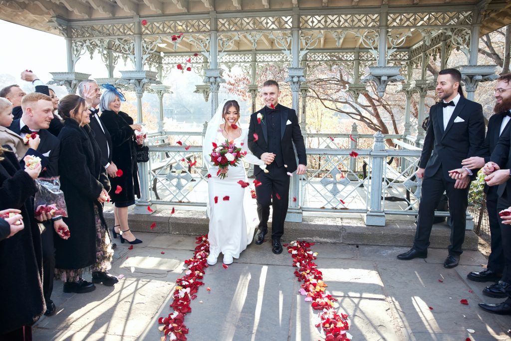 Beautiful wedding day. Bride and groom step out of the Ladies Pavilion while all the guests throw rose petals at the happy couple.